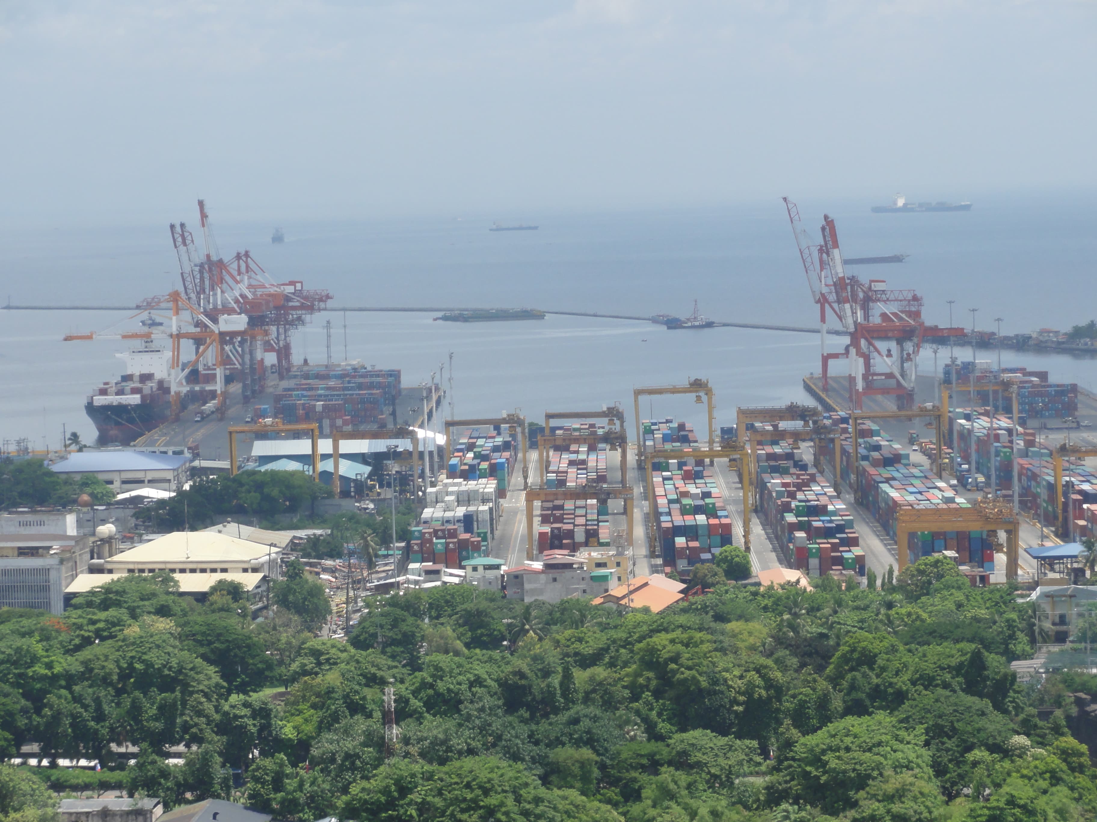 Aerial view of an international container port with cranes, stacked containers, and vessels at berth