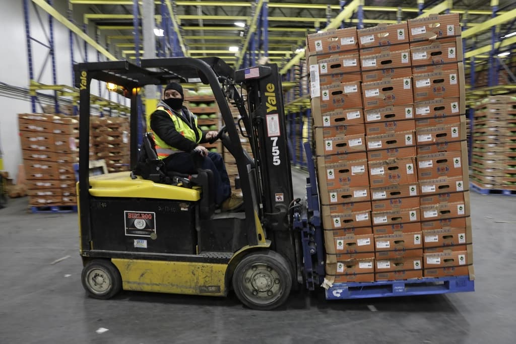 Forklift operator moving a palletized load of consolidated cartons in a warehouse